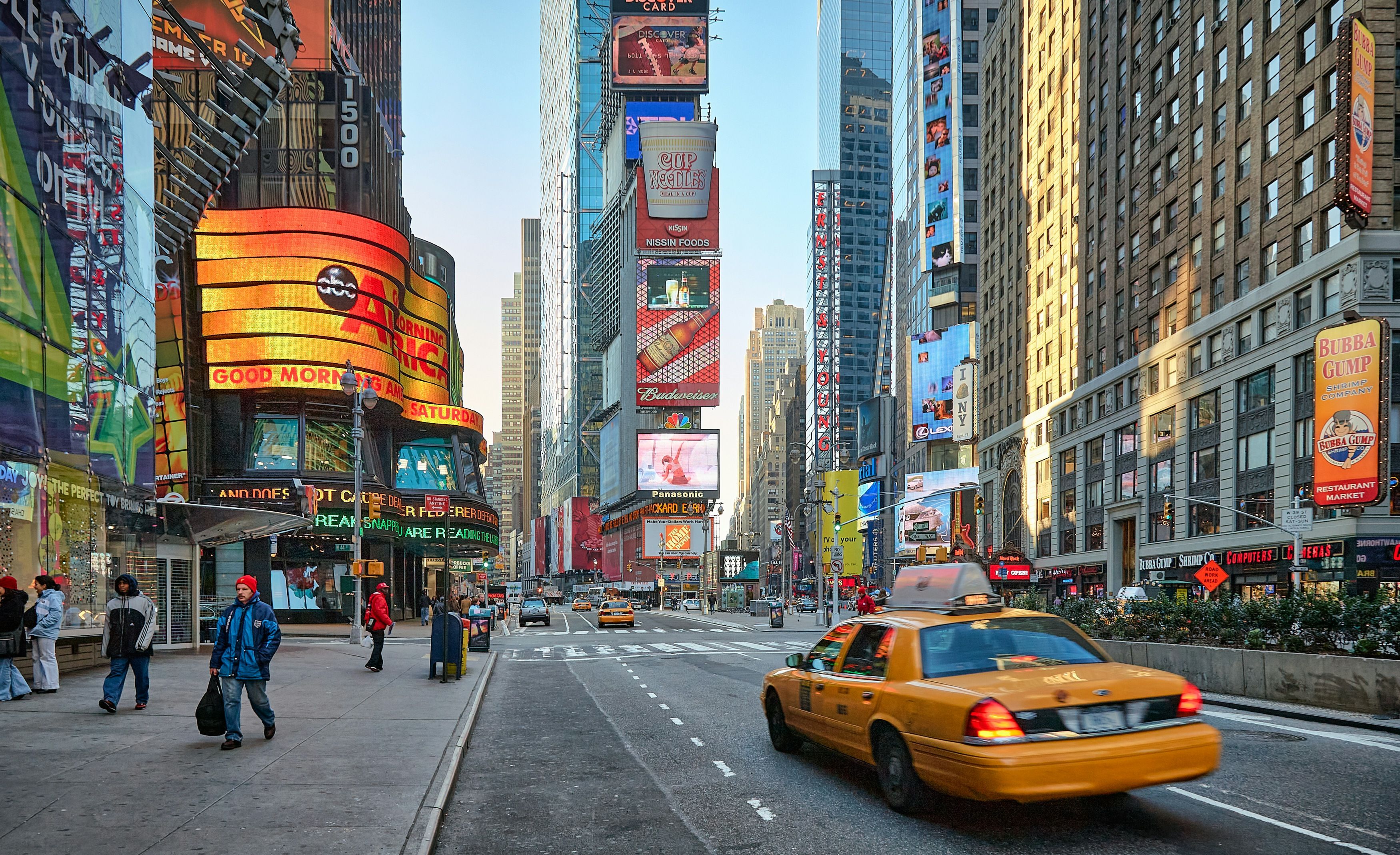 A yellow taxi passing the billboards and buildings of Times Square, New York.