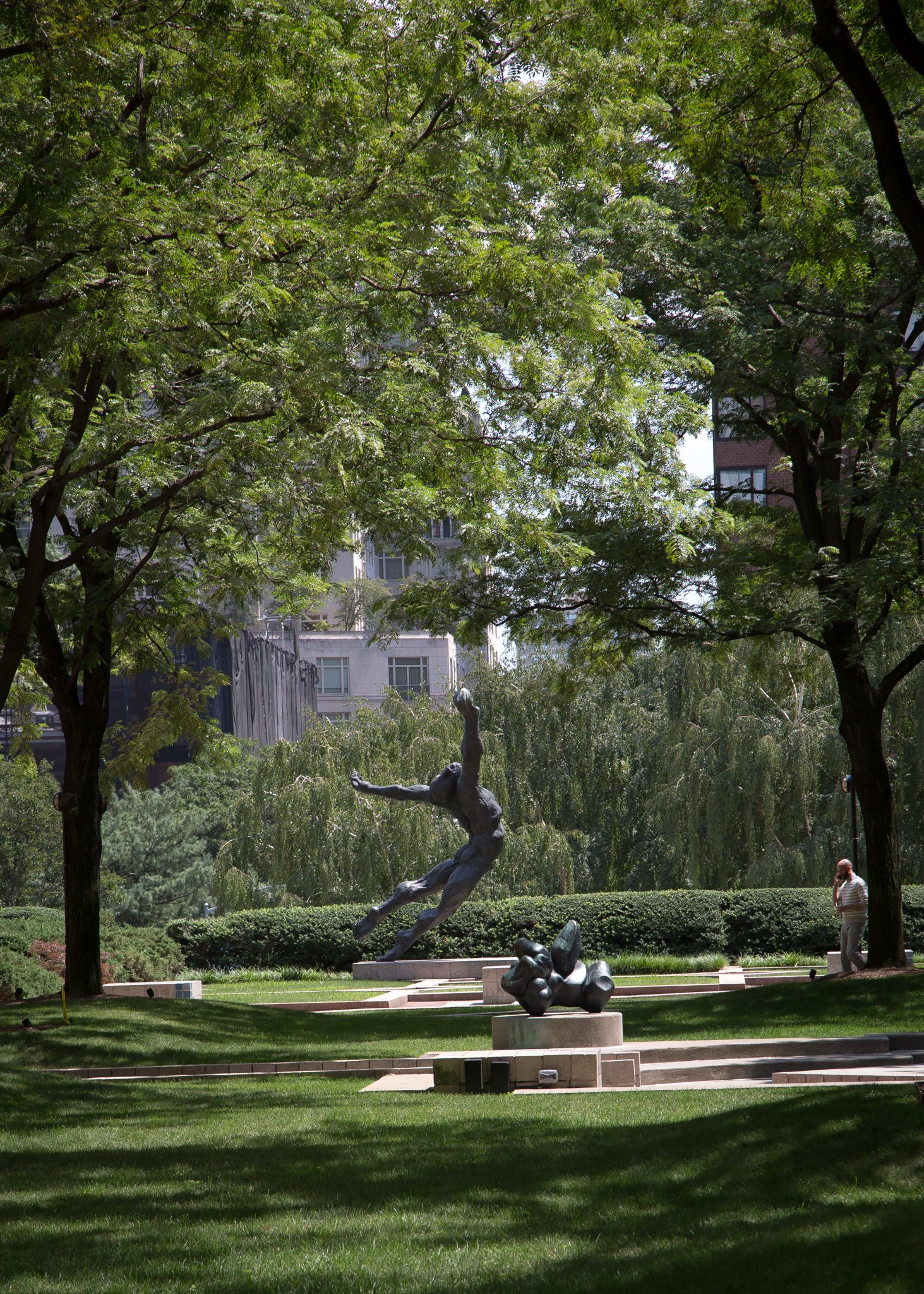 Garden plaza with trees and a sculpture at Fordham Lincoln Center