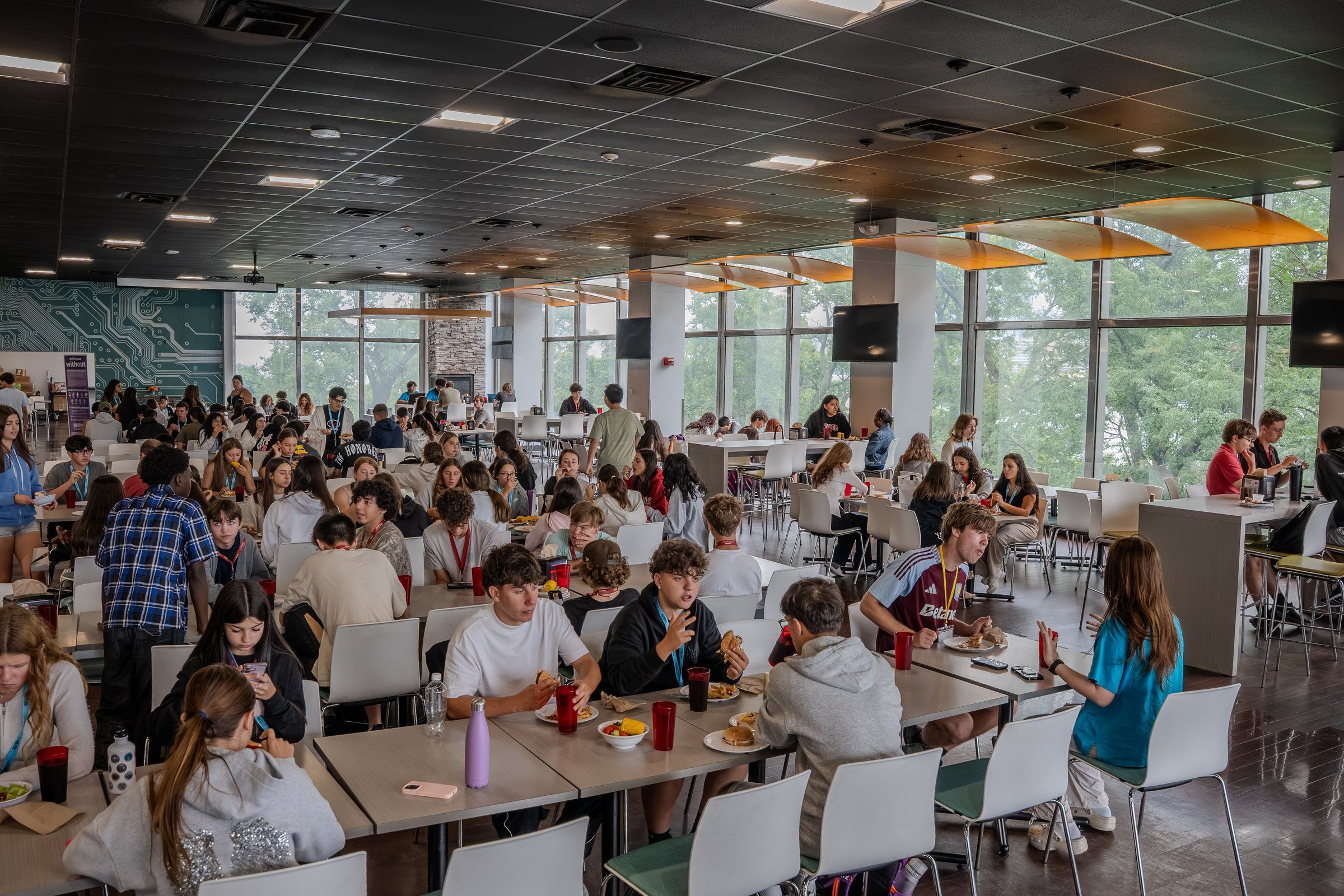 A busy, bright dining hall with students eating at long tables at Stevens