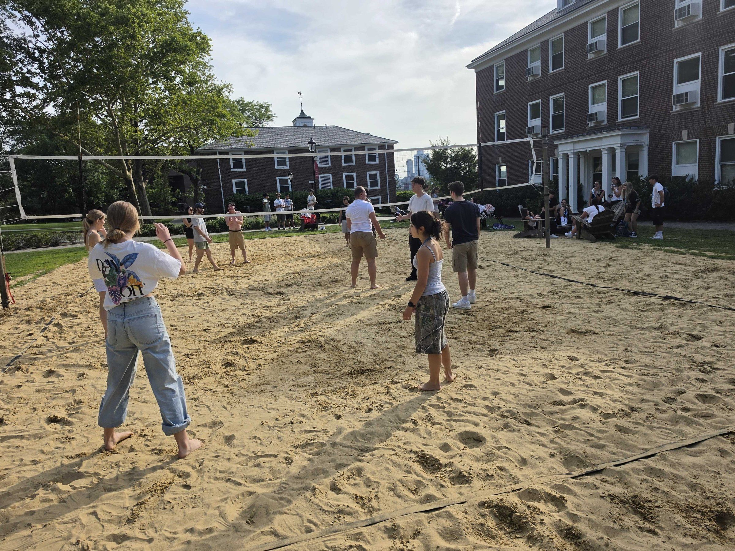 Students playing beach volleyball on the Stevens campus sand court