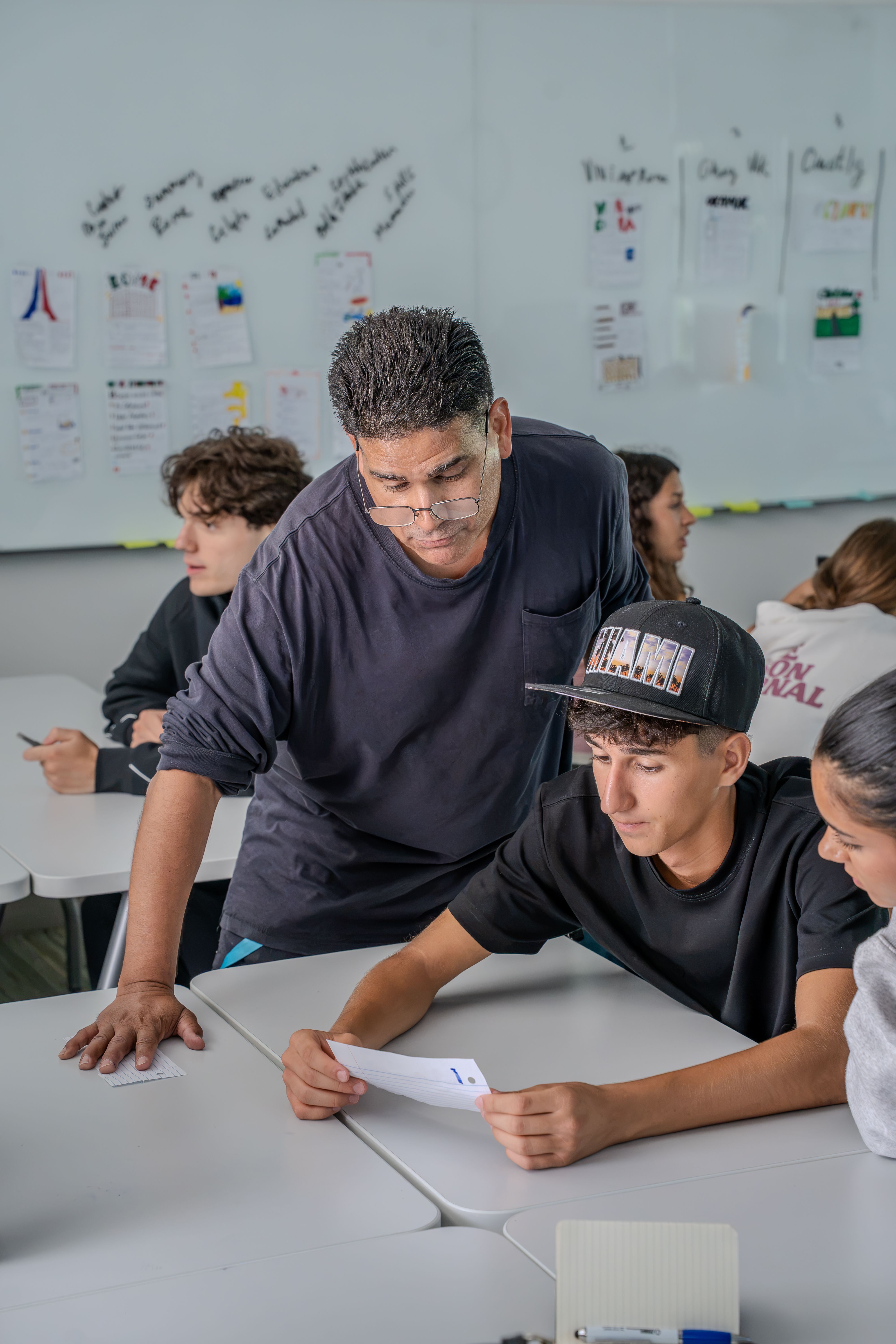 Teacher helping a student with written classroom work in Miami