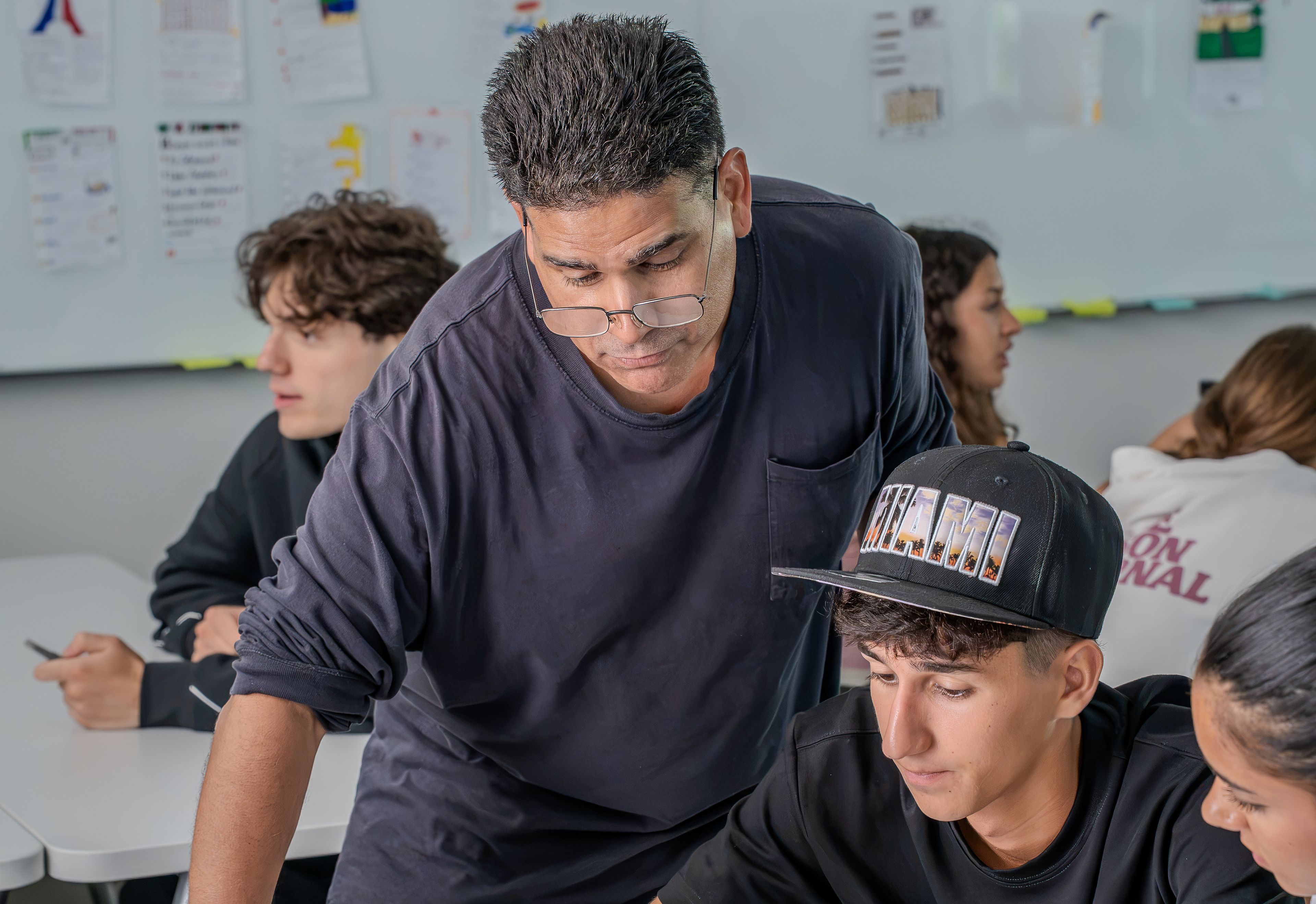 Teacher helping a student with written classroom work in Miami