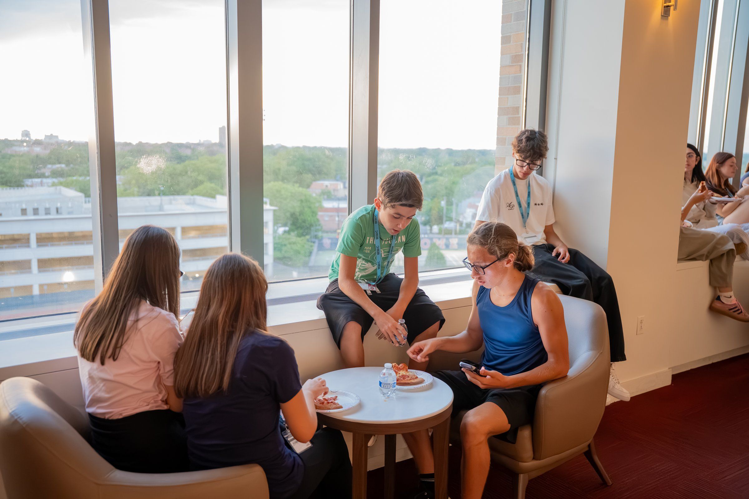 Students relaxing in a lounge with big windows over Queens