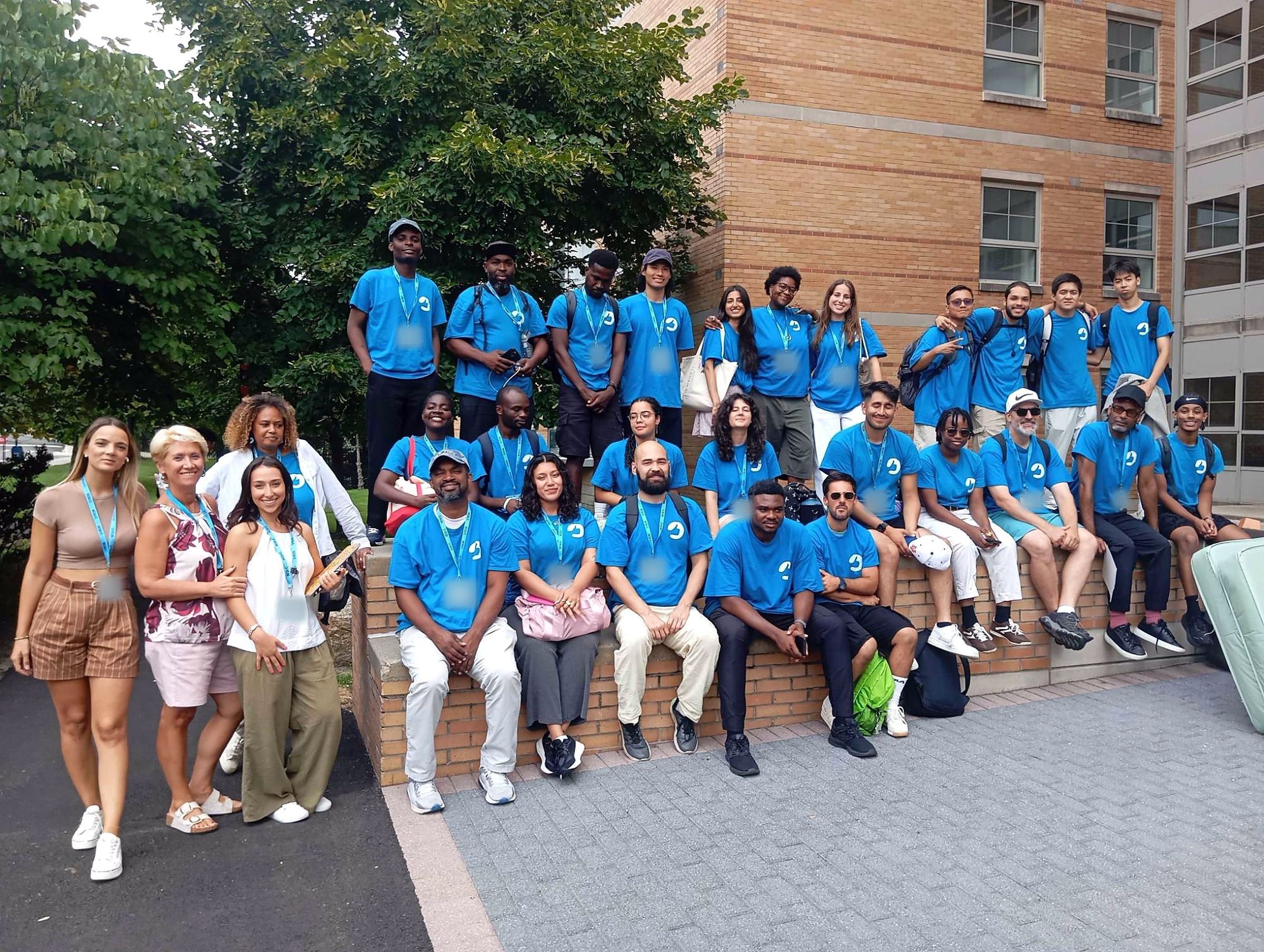 The YES USA St. John’s staff team in blue YES USA shirts and lanyards outside a residence hall