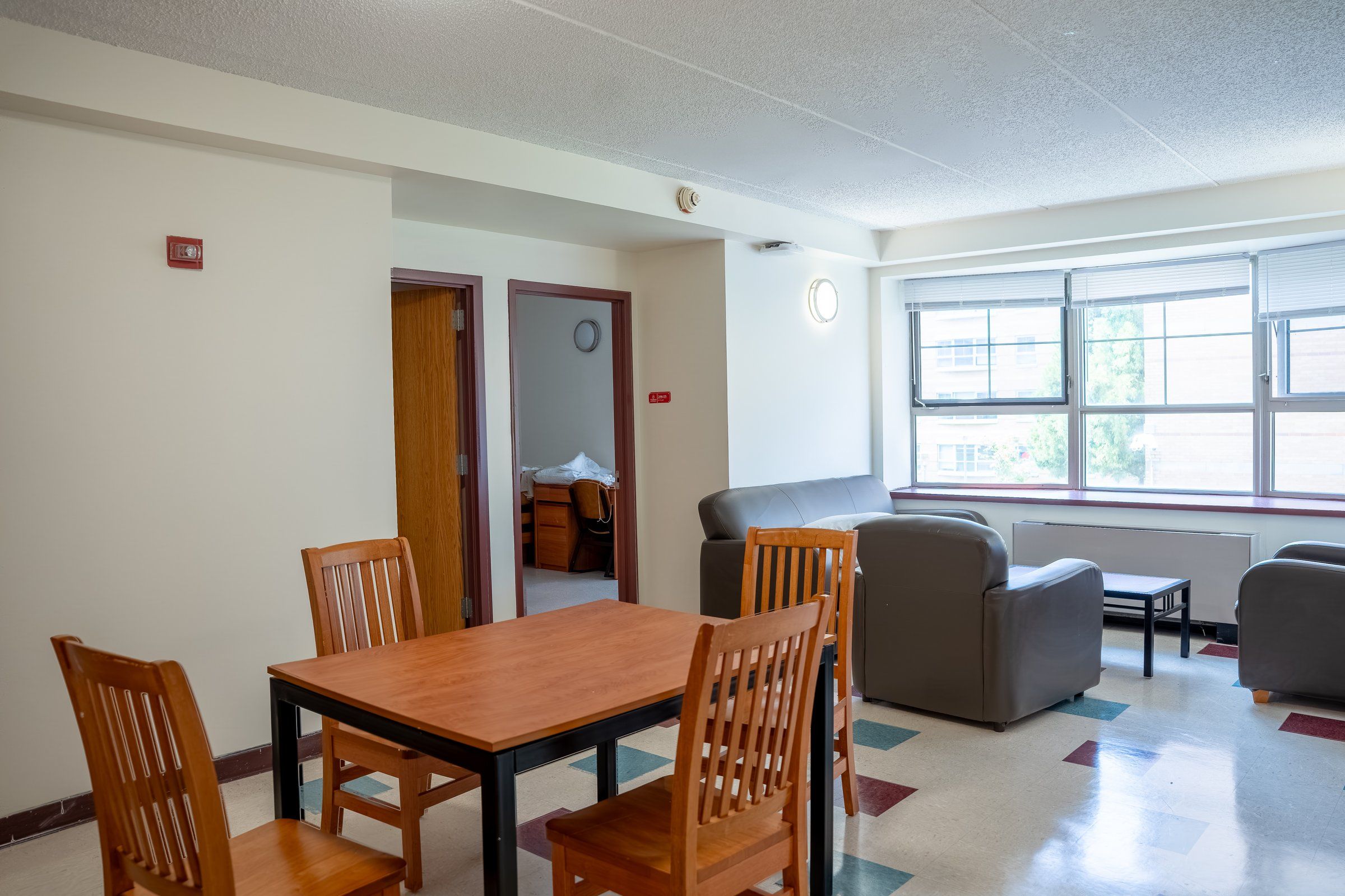 Suite common room with a dining table, armchairs and large windows in a St. John's residence
