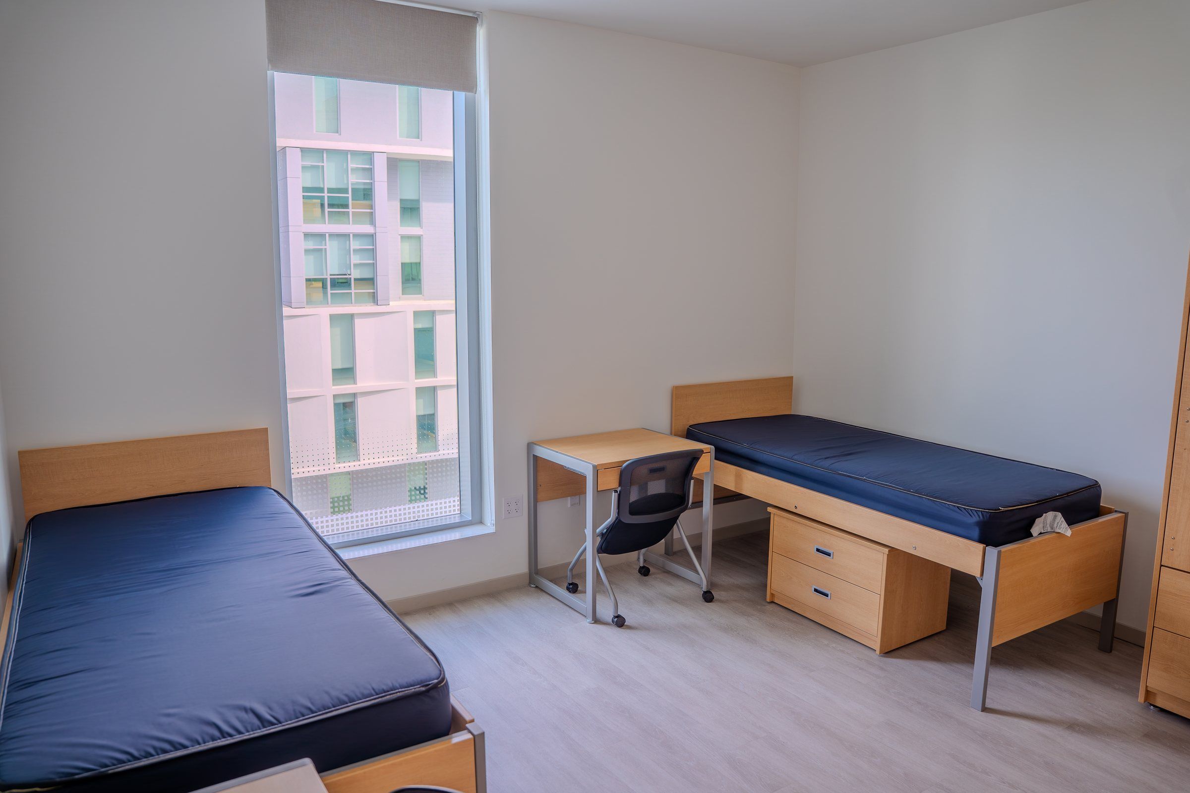 Residence room with two beds, desks and a tall window