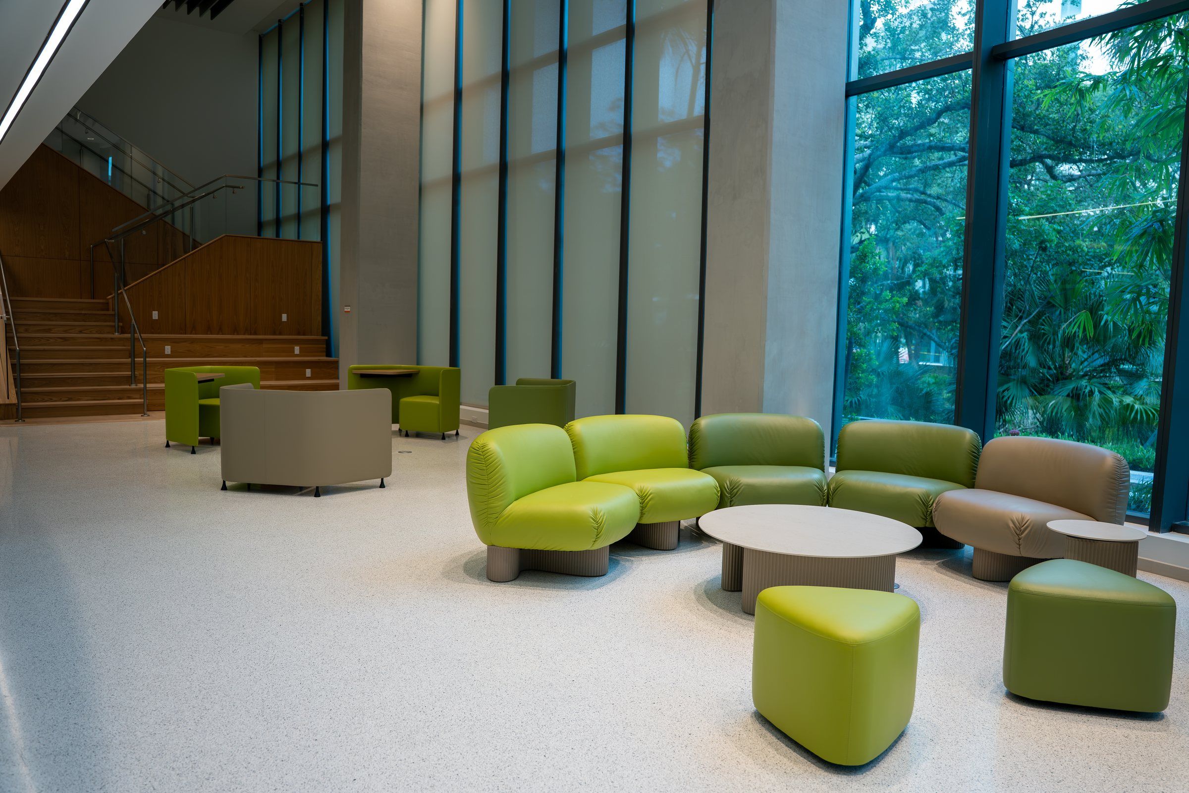 Double-height residence lounge with green seating and a staircase