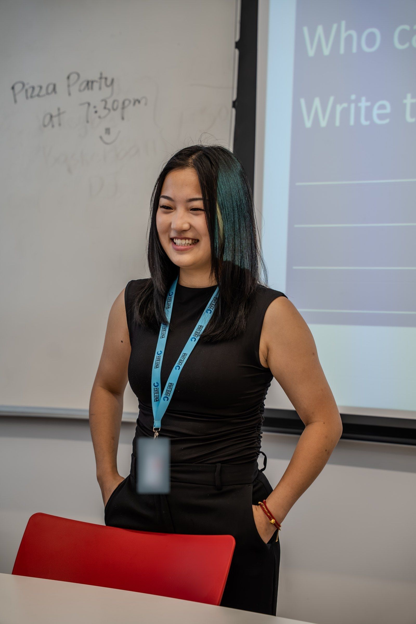 A YES USA teacher with a staff lanyard smiling in a classroom