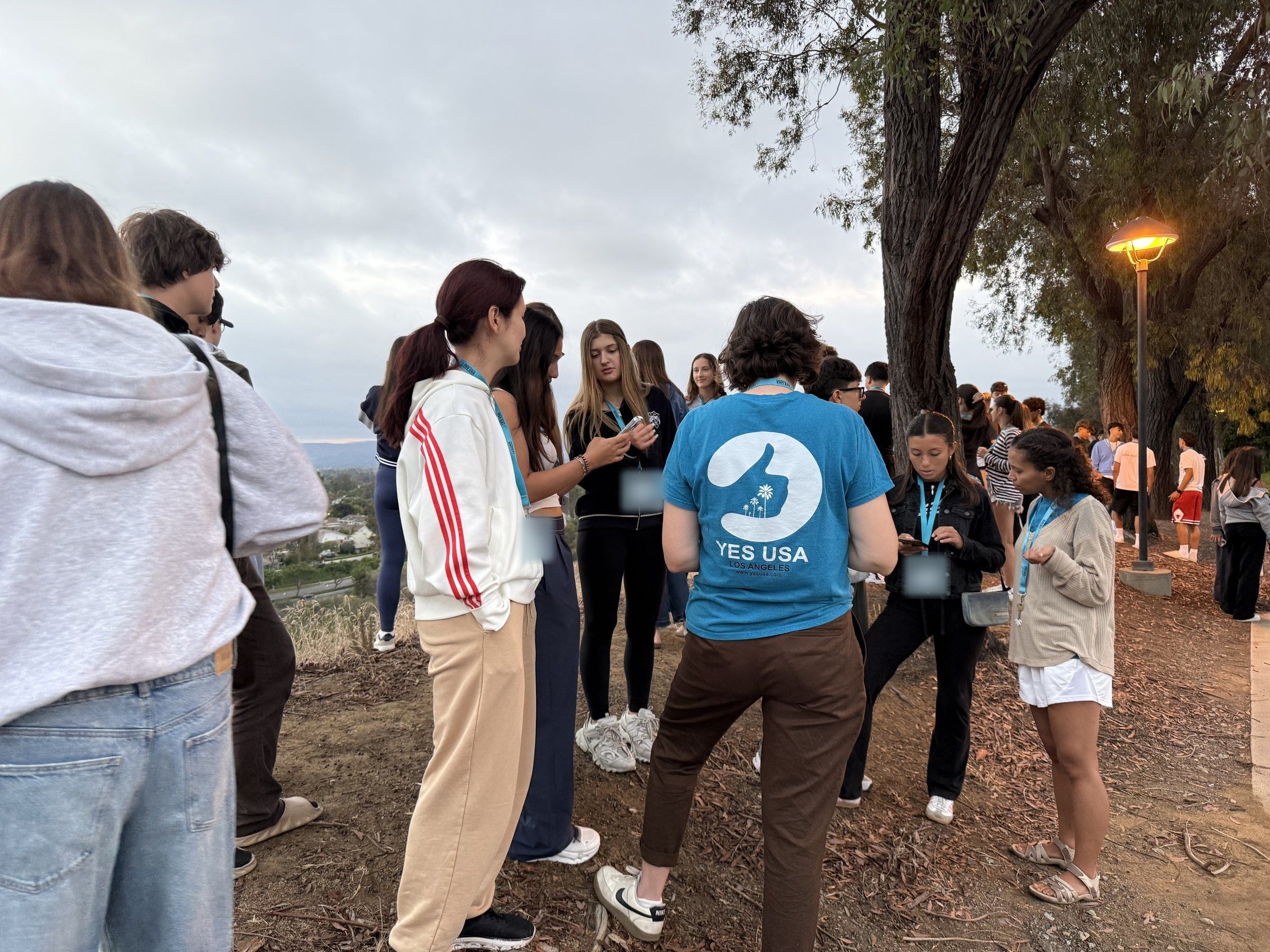 A YES USA staff member gathering students outdoors at dusk at Concordia
