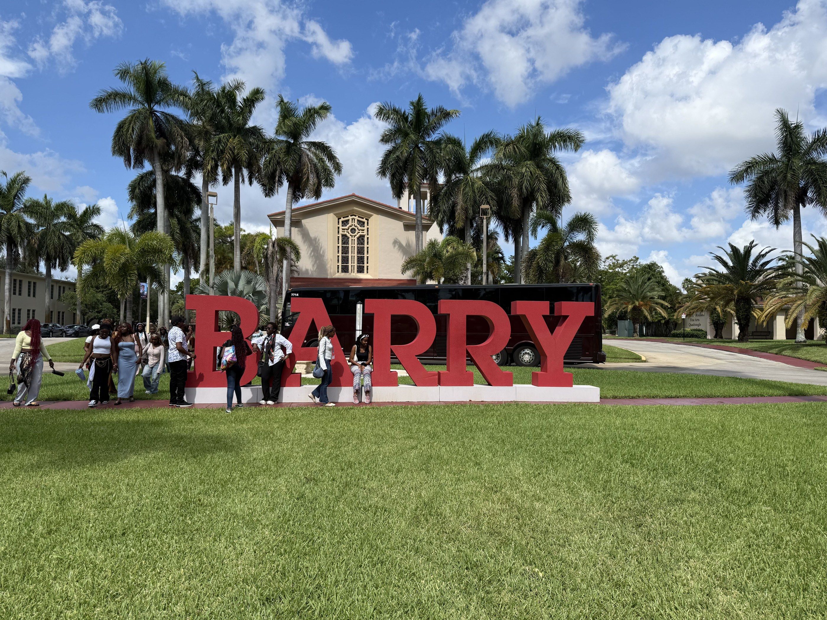 A YES USA group at the Barry University sign, with the campus chapel behind