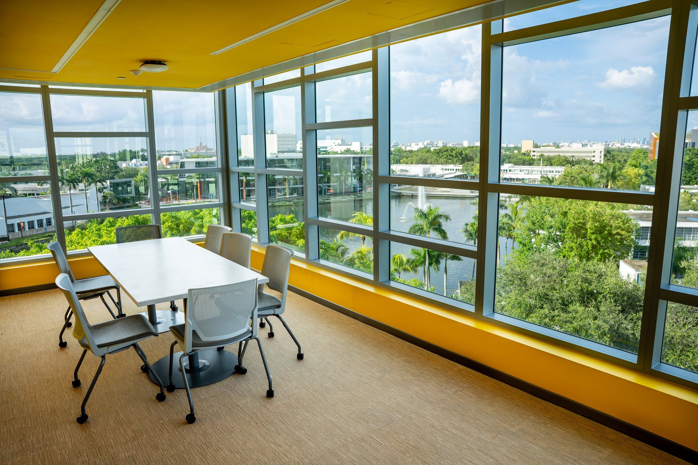 A study room in the University of Miami residence with tables and a wide view over the campus