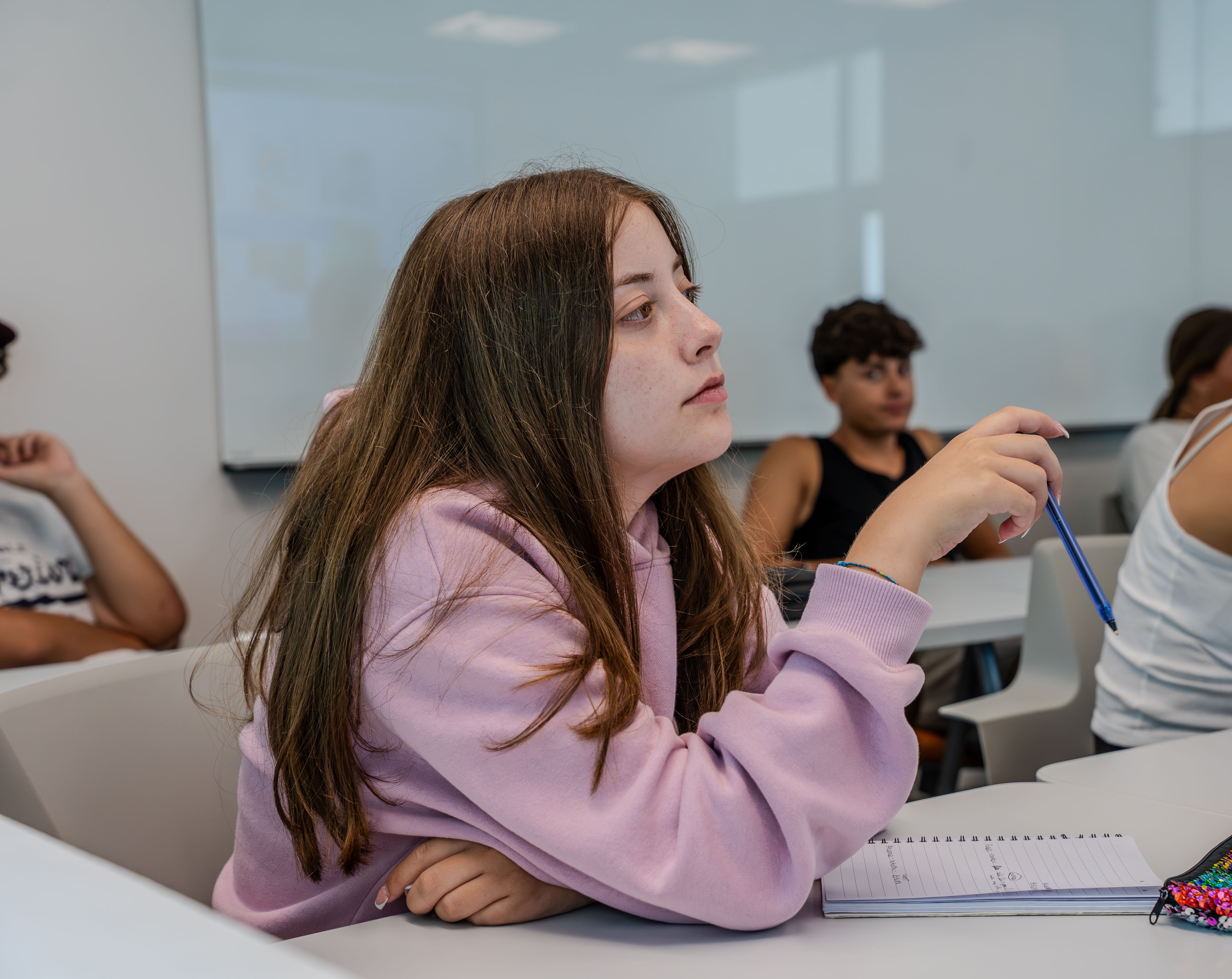 Student listening with a pen and notebook during a Miami summer lesson