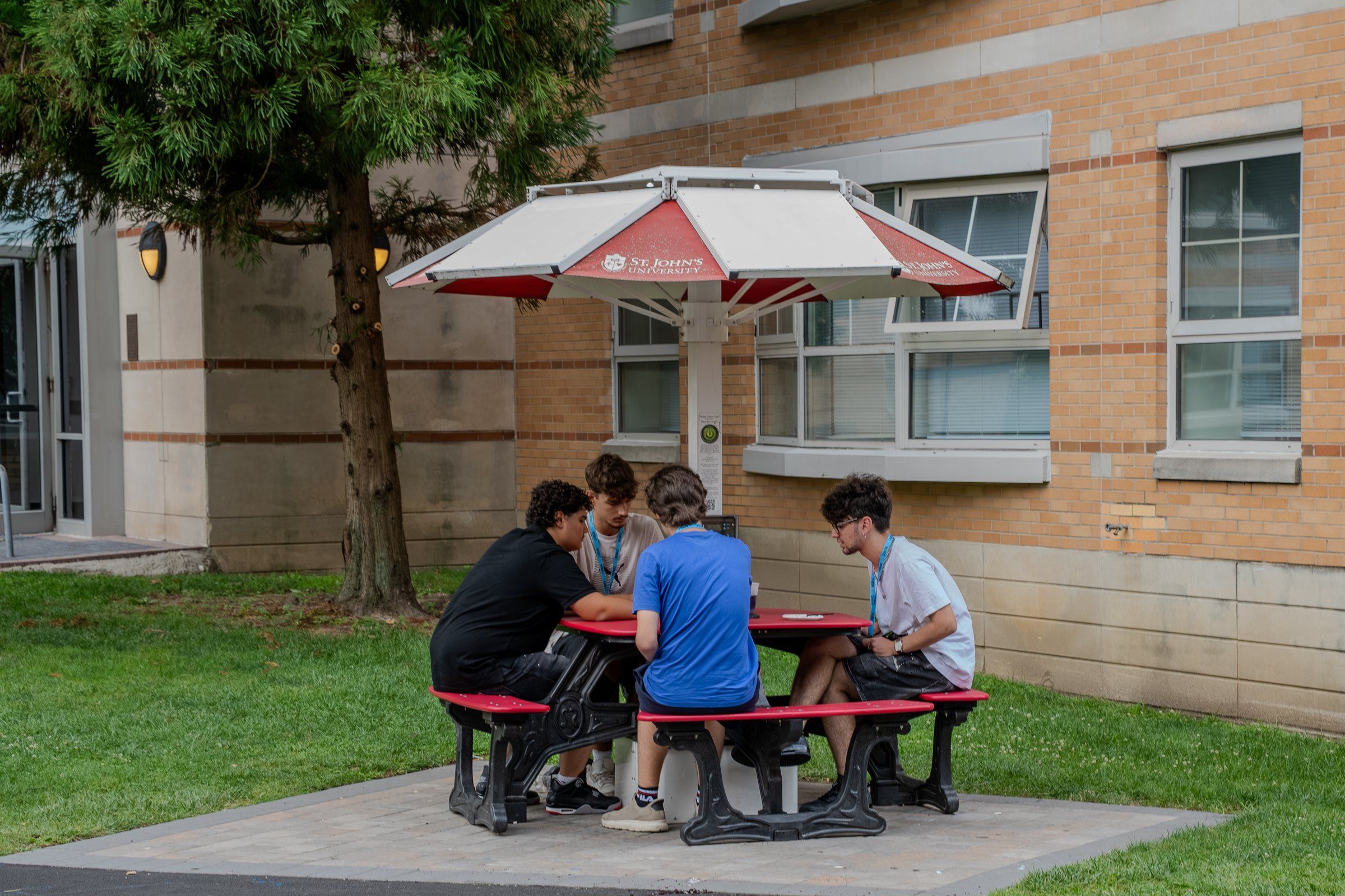 Students chatting at a picnic table beside a St. John's residence hall