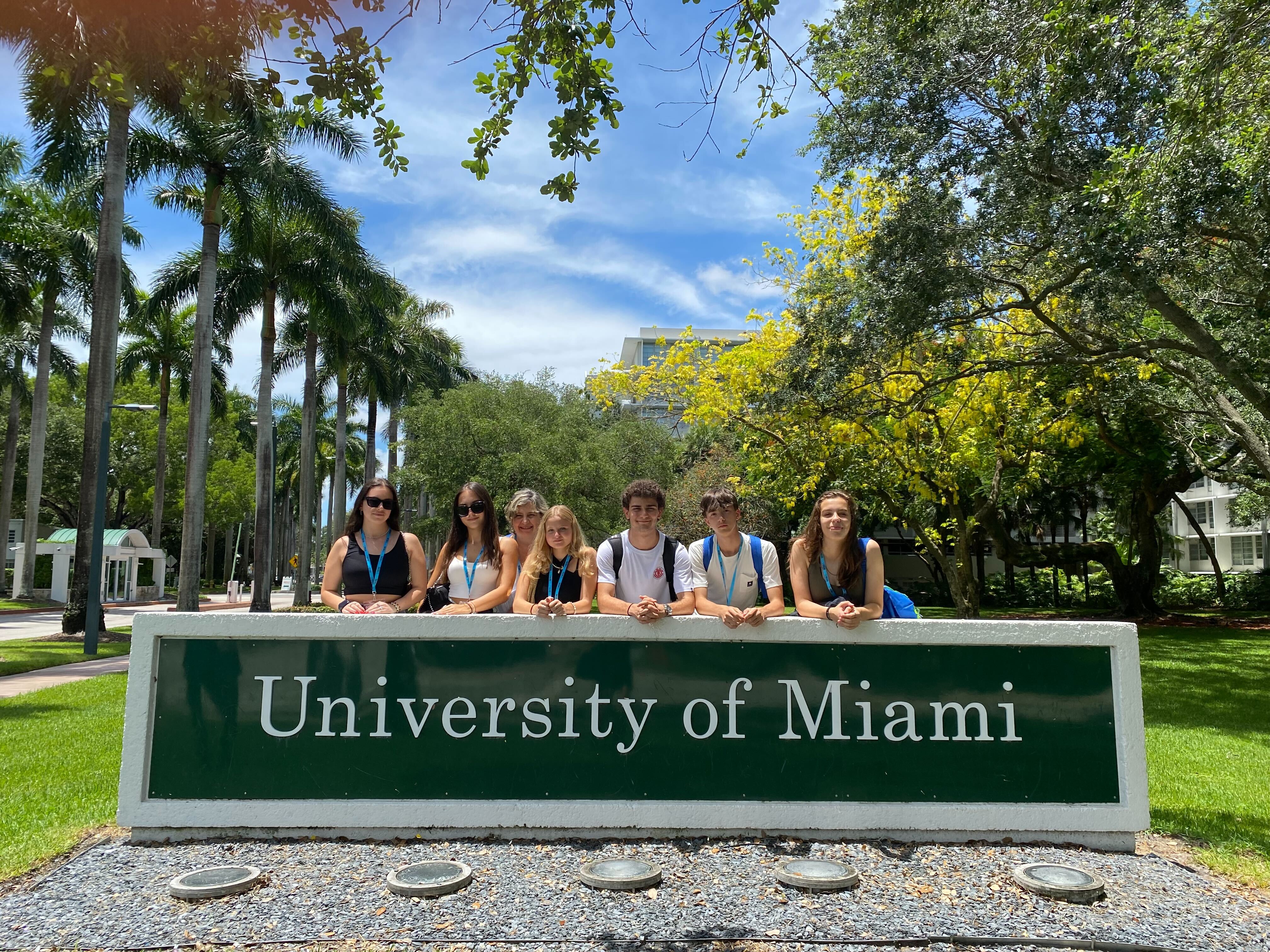 Students beside the University of Miami campus sign