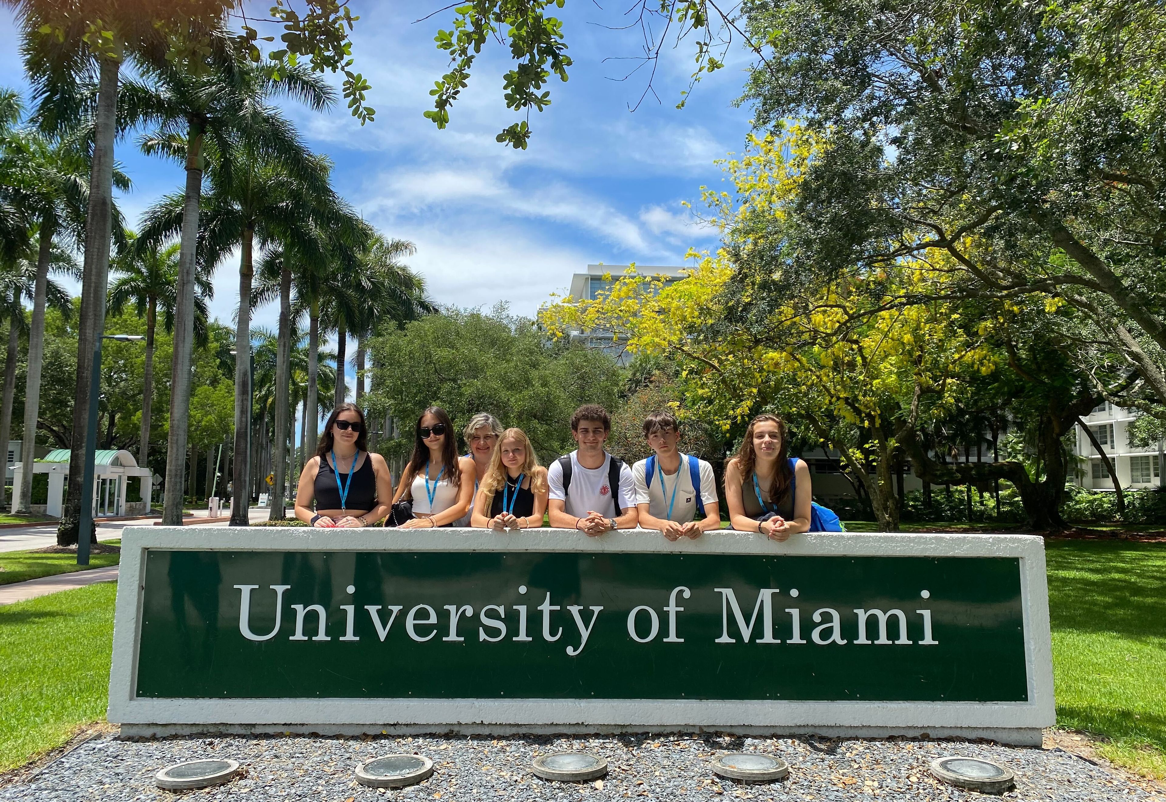 Students beside the University of Miami campus sign