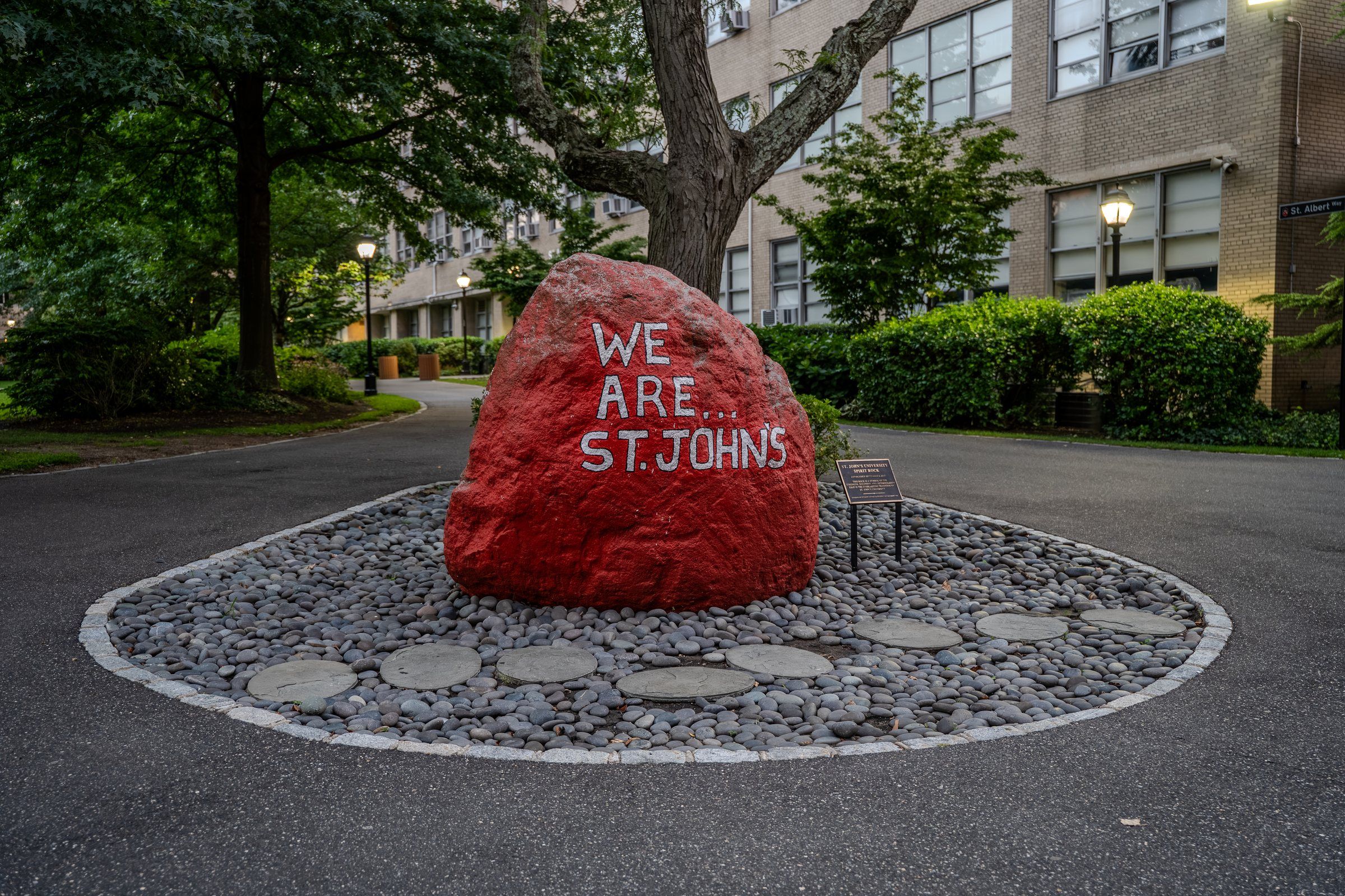 The red "We Are St. John's" rock on campus at dusk