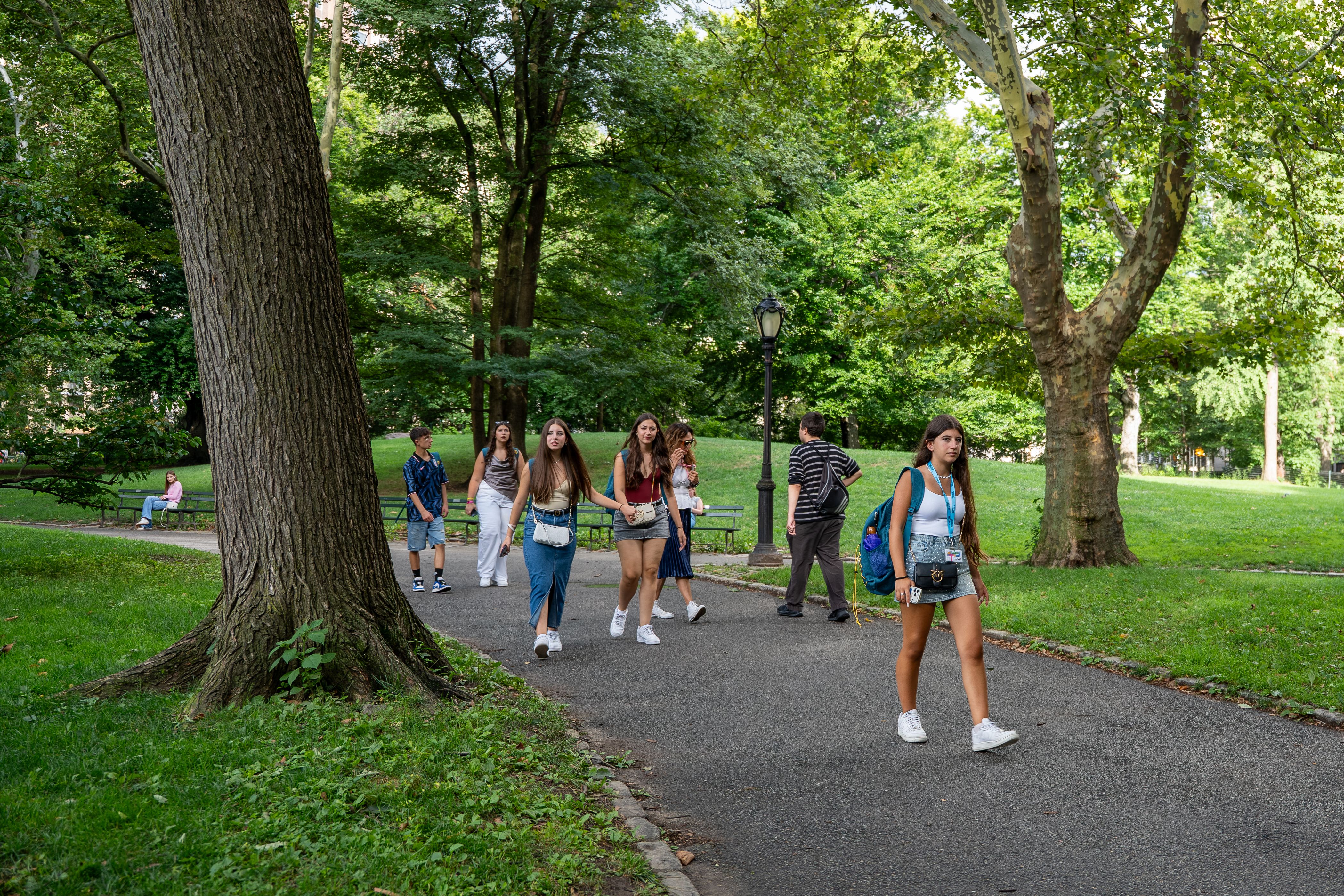 YES USA students wearing blue lanyards walking along a tree-lined park path