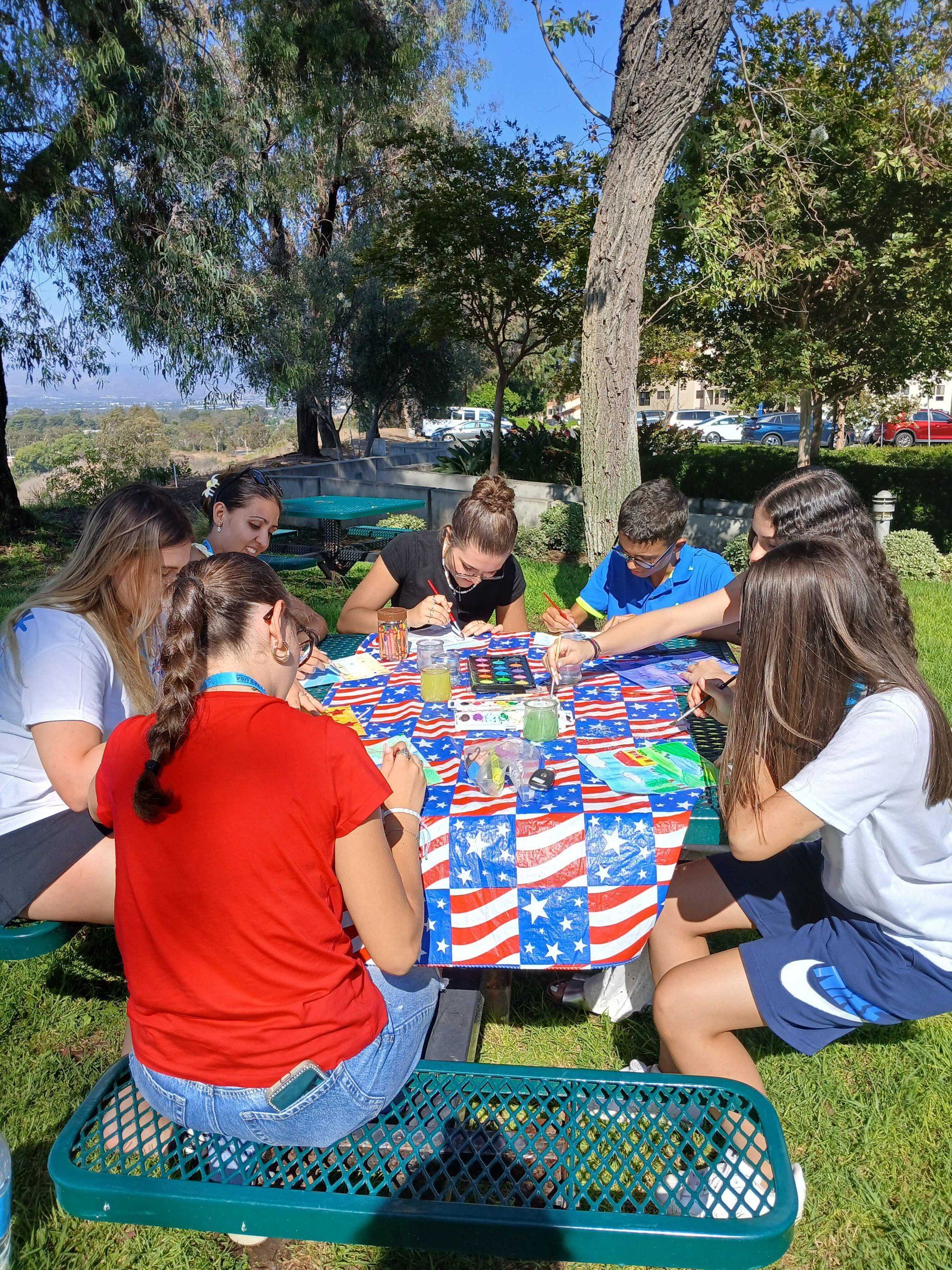Students playing cards at a picnic table on the lawn