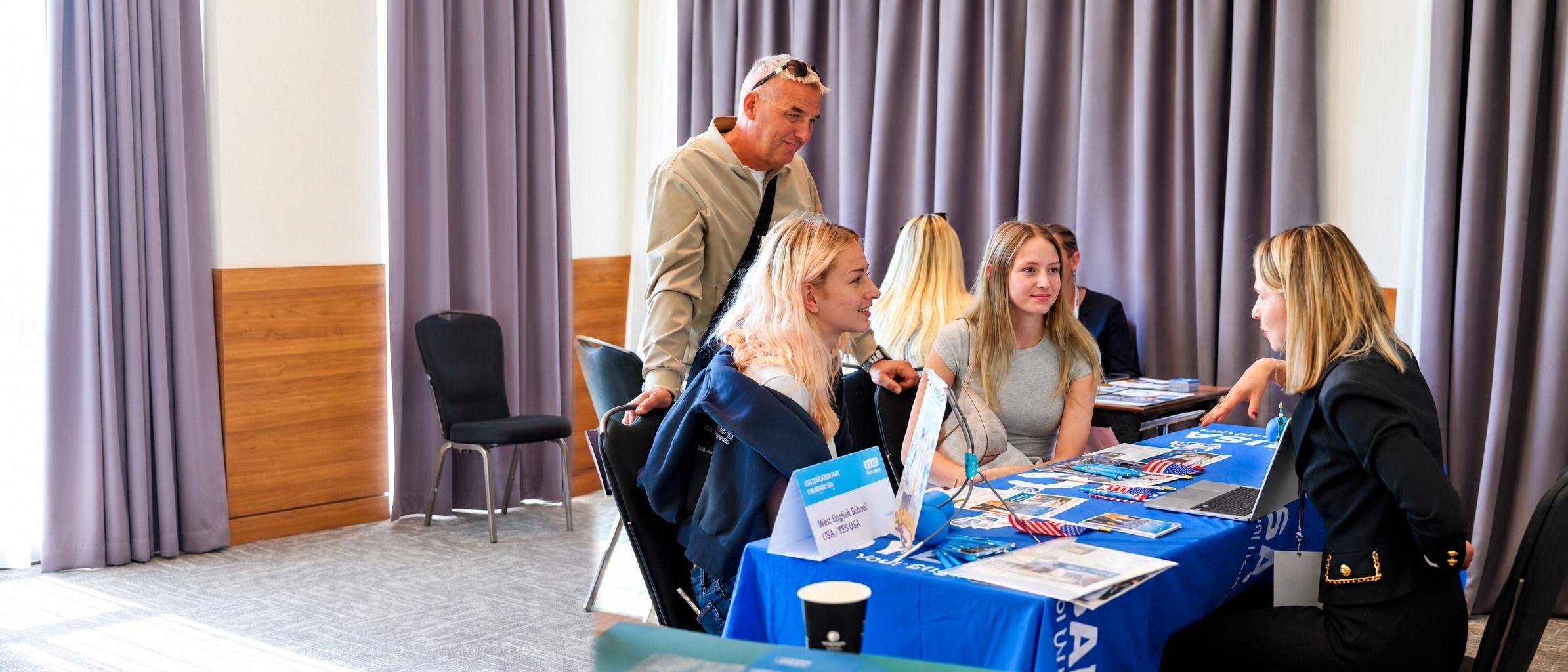 A YES USA representative talking with a family at the YES USA table during an education fair in Croatia