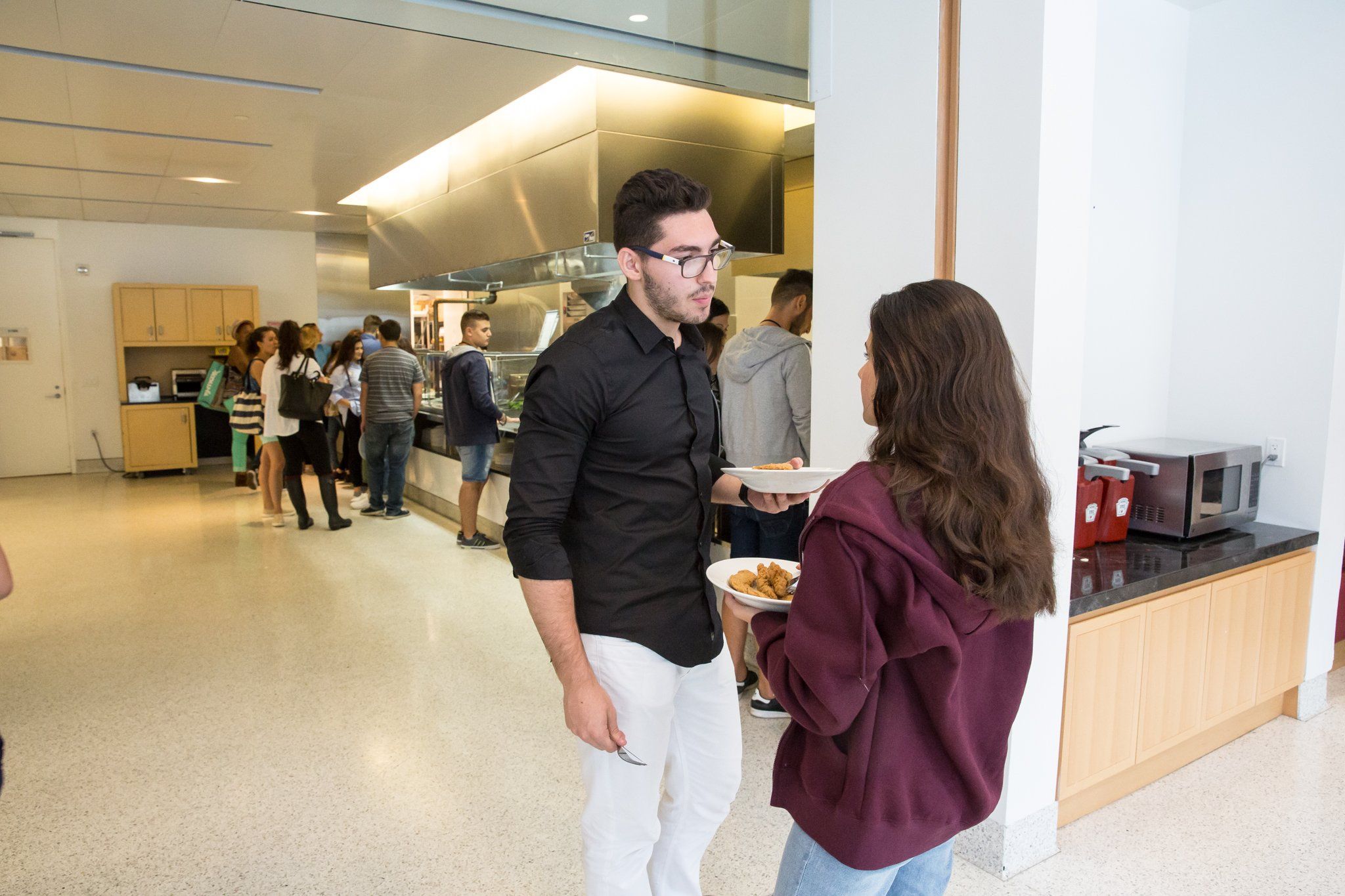 Two students chatting with lunch plates in the cafeteria
