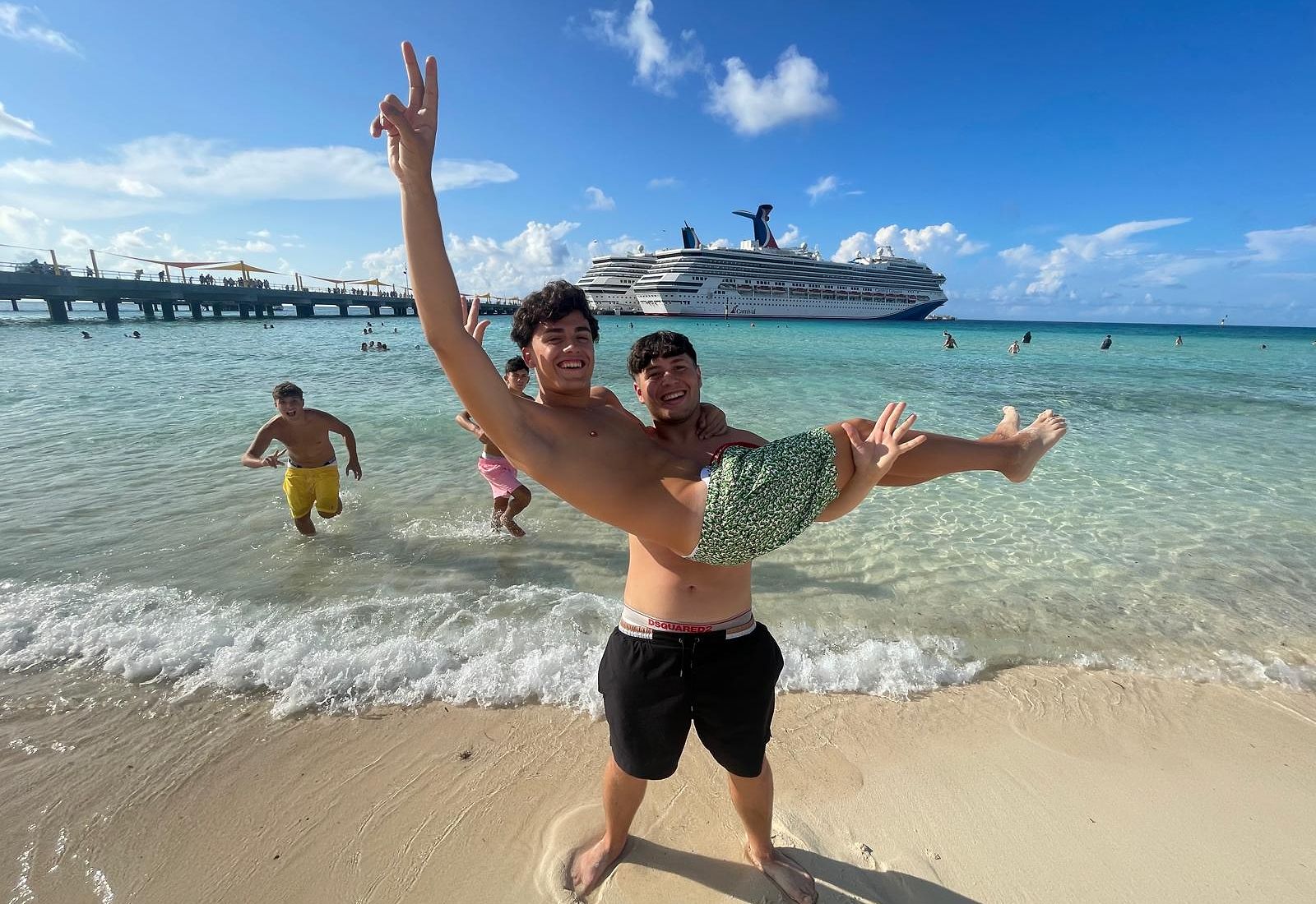 Students enjoying the beach with a cruise ship in the background.