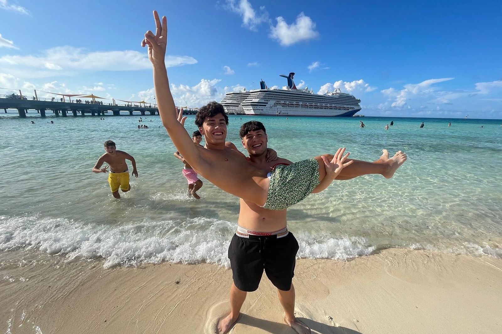 Students enjoying the beach with a cruise ship in the background.