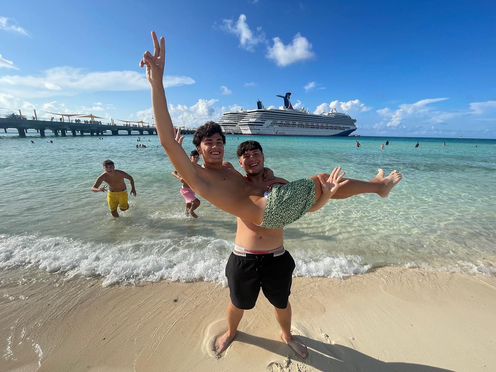 Students enjoying the beach with a cruise ship in the background.