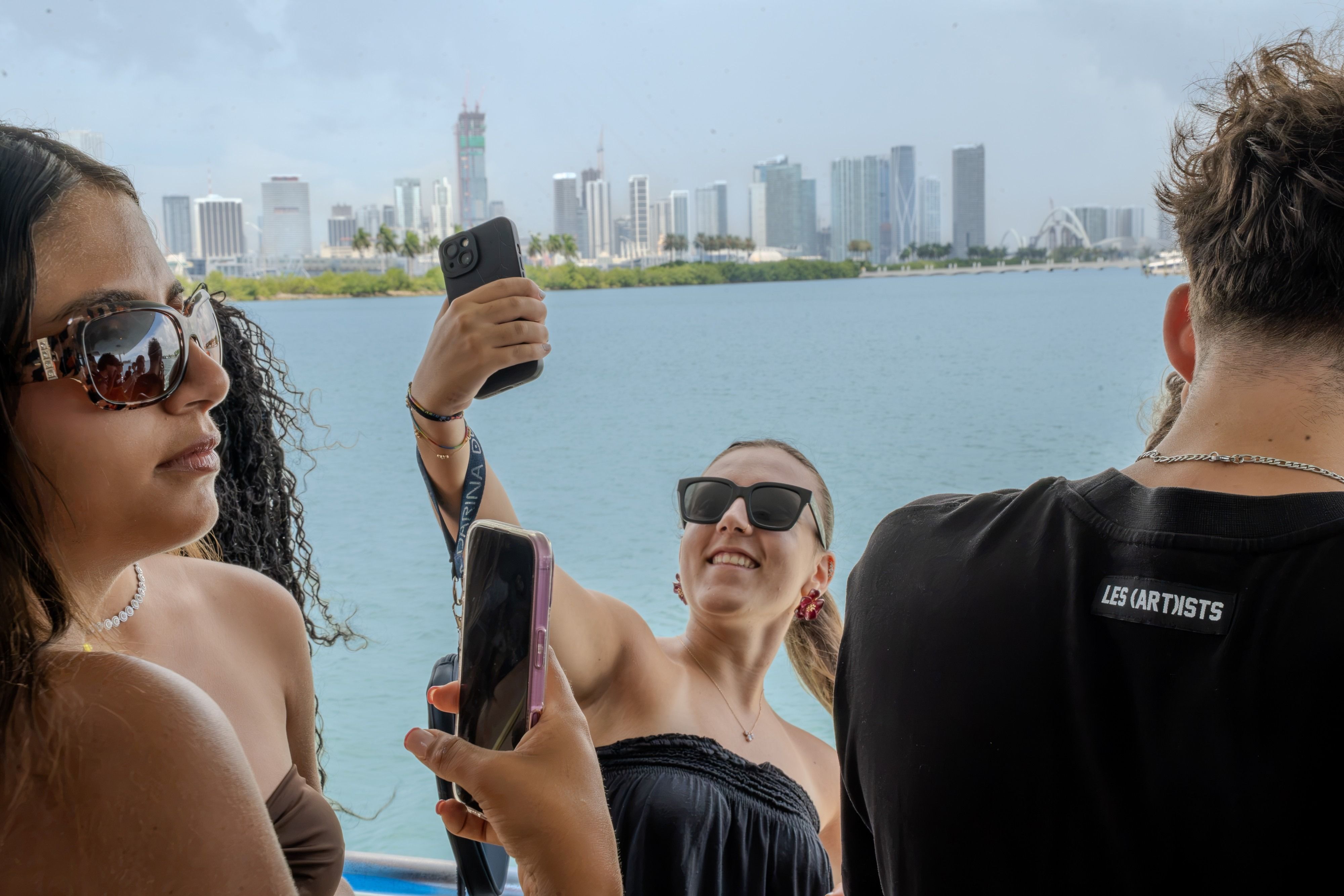 YES USA students taking photos on a boat in Biscayne Bay, with the Miami skyline behind