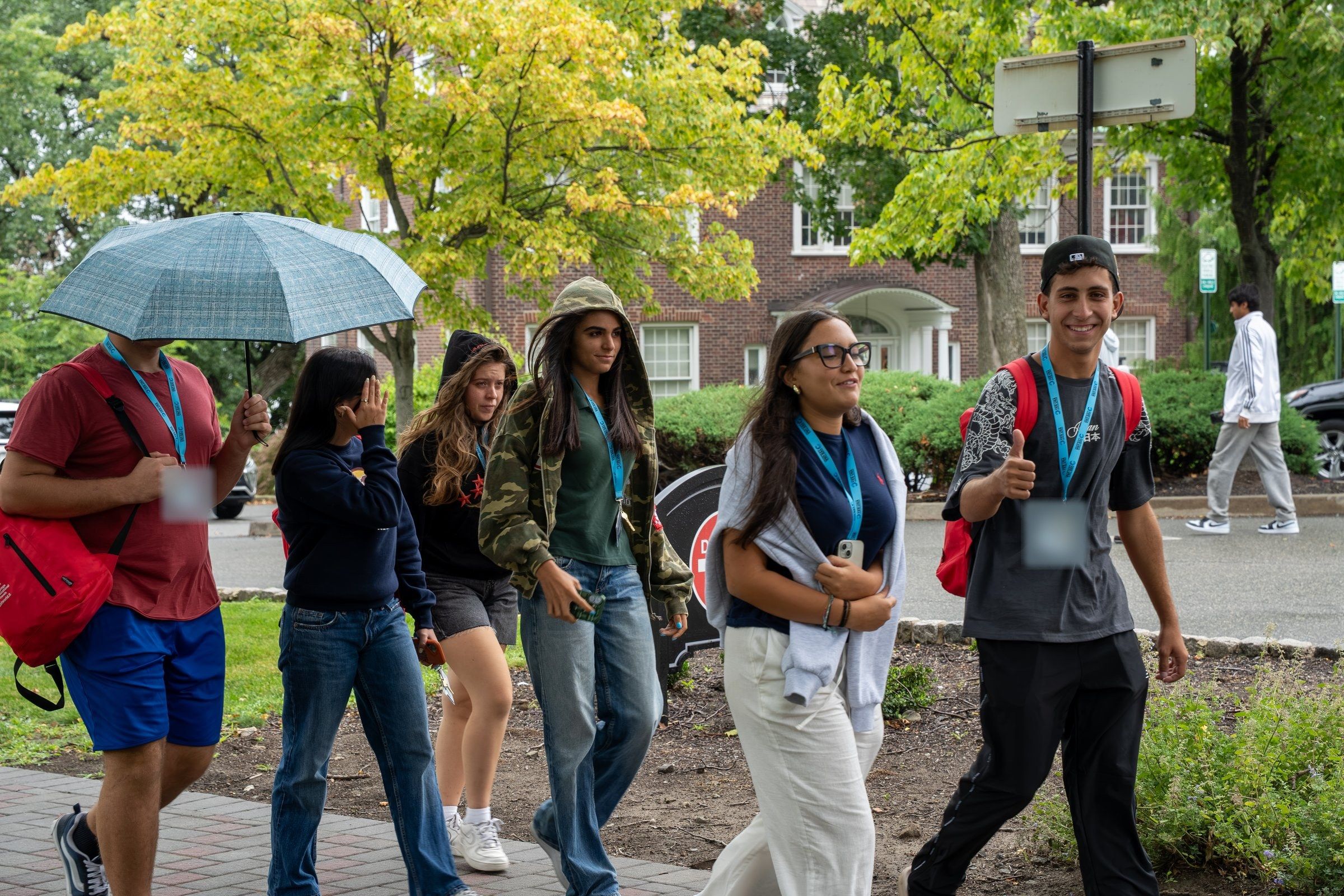 YES USA students walking across the Stevens campus, one giving a thumbs-up