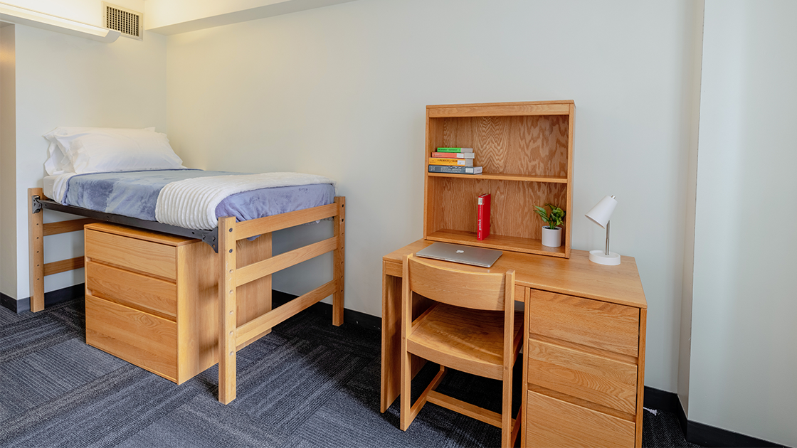 Bed and desk in a Suffolk University Miller Hall residence room