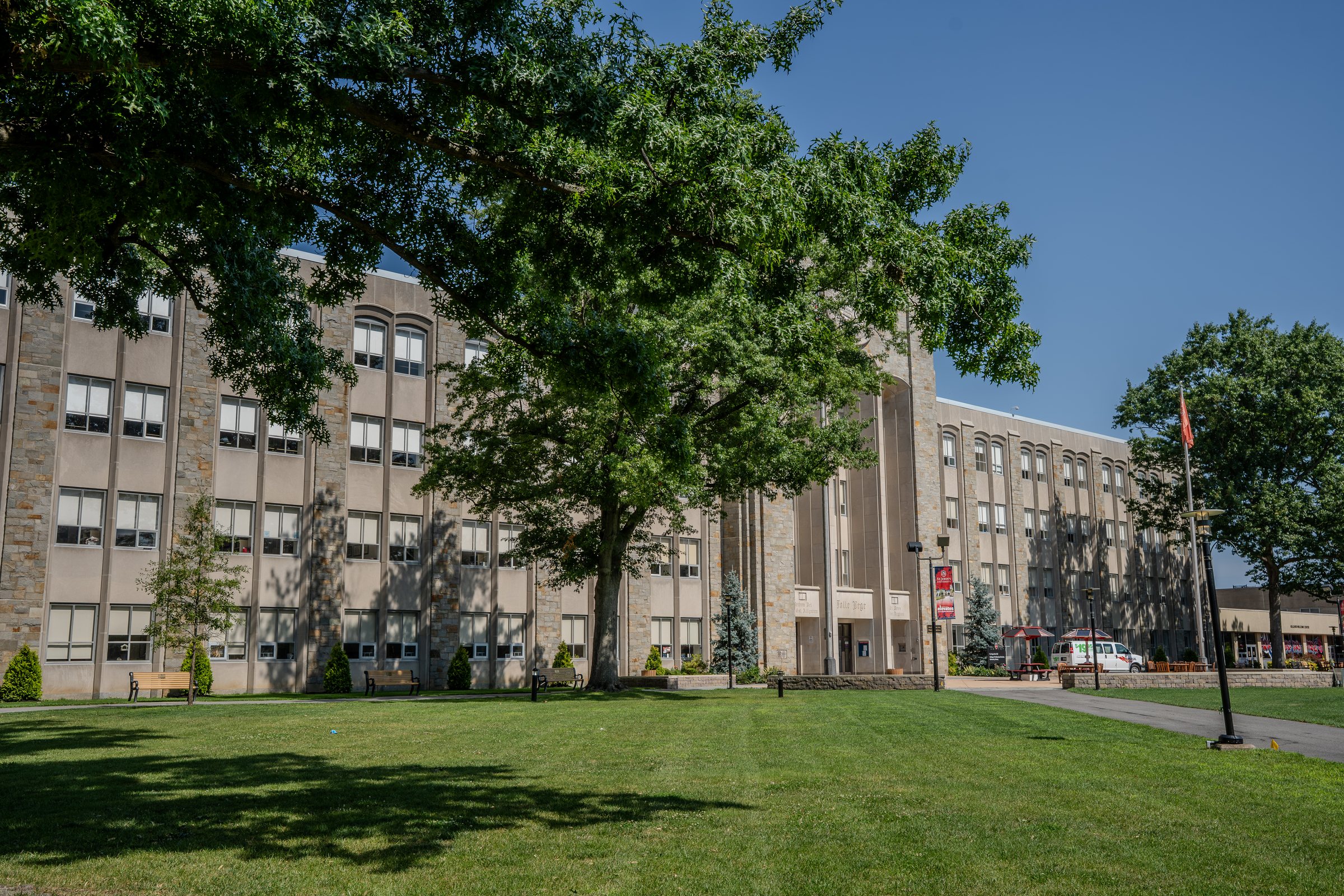 Green lawn and a large tree in front of an academic building at St. John's University