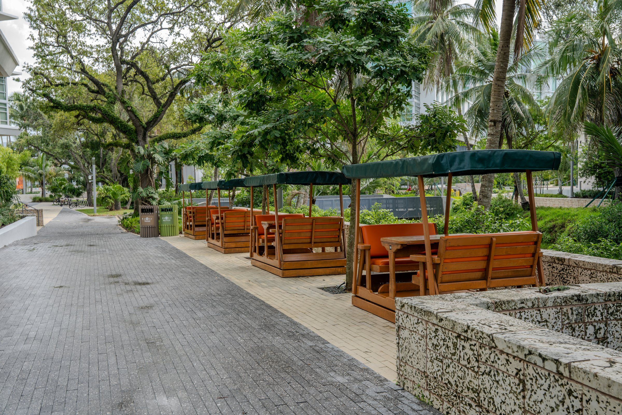 Shaded walkway with wooden cabana seating among tropical trees
