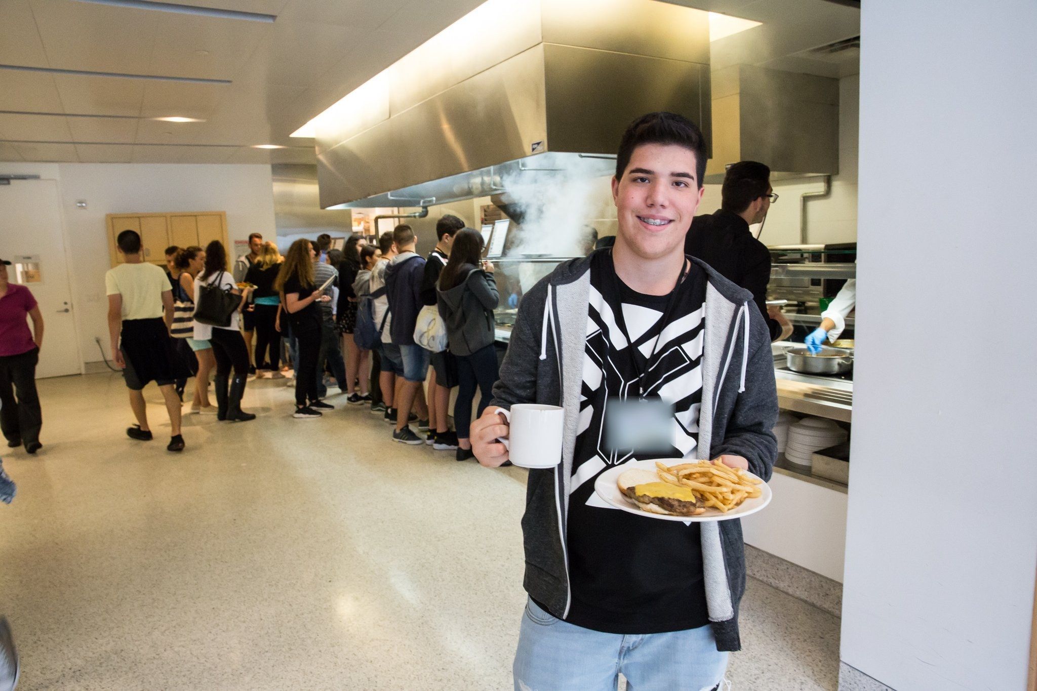 A smiling student with his lunch plate in the Fordham cafeteria