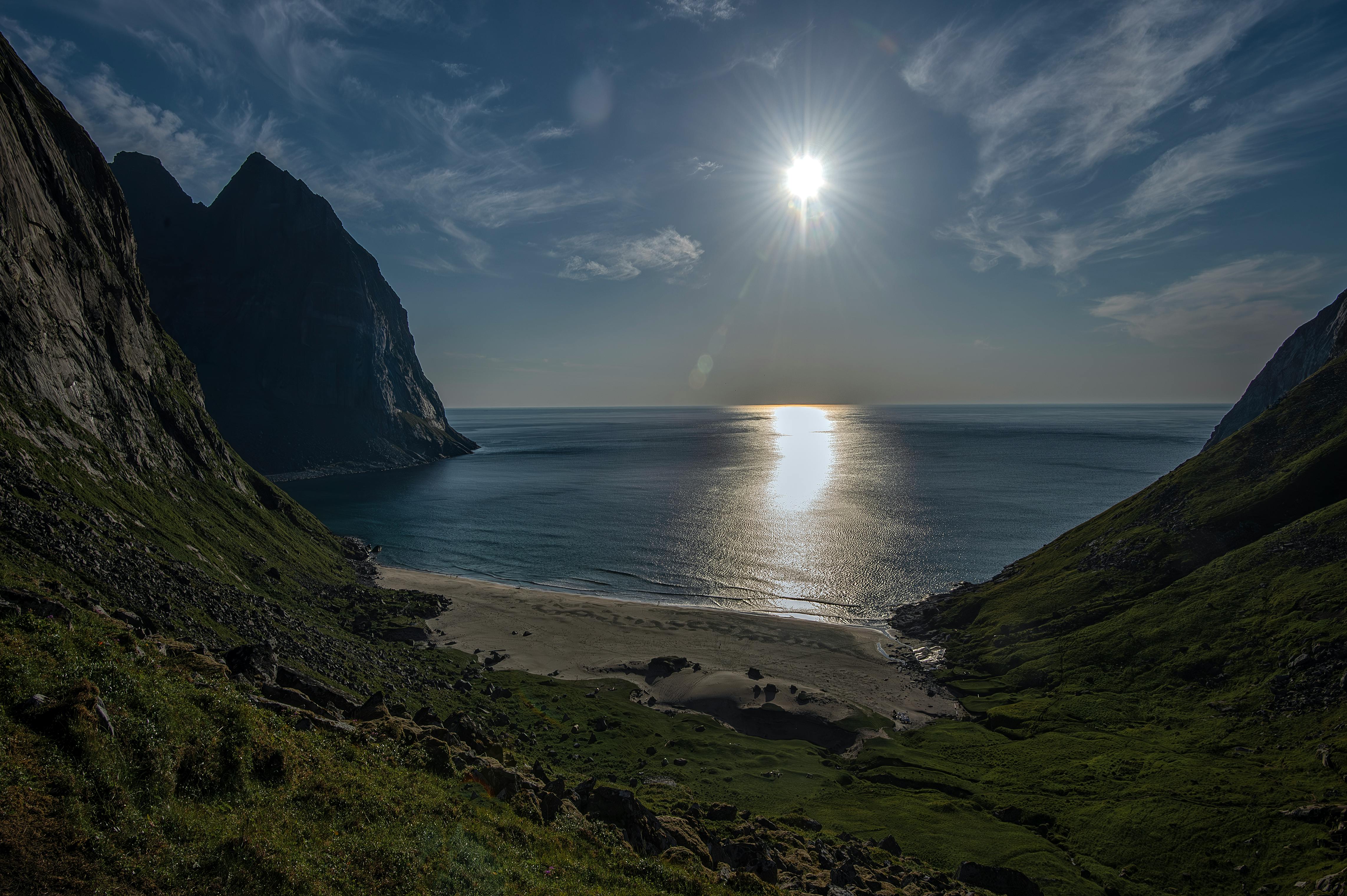 Bilde fra fjorden og kysten langs Lofoten. Sol, fjell og grønt gress.