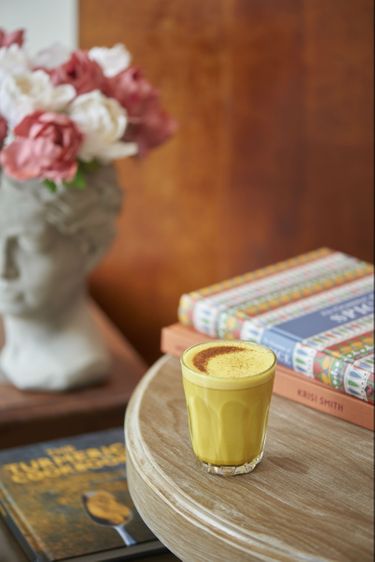 Turmeric milk sitting on top of some books in a cafe 