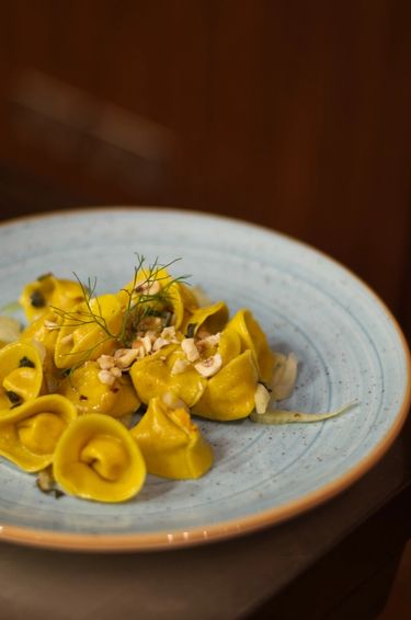 A plate of fresh tortellini on a light blue ceramic plate