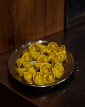 A tray full of fresh ravioli on a kitchen workstation