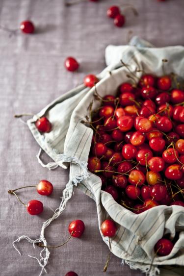 A fabric bag filled with red cherries 