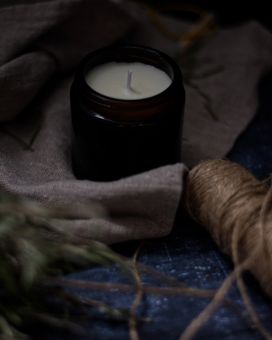 Candle on linen surrounded by natural thread 