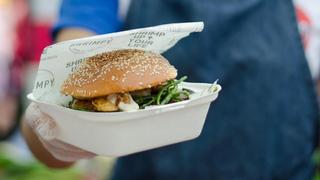 Close up of a hand presenting a burger in a burger box with Shrimpy's food wrap — a London food stall