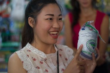 Woman explaining an Asian product to a crowd at an Asian wet market