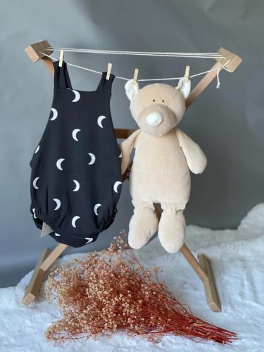 Picture of a baby onesie with a moon print in navy hanging beside a soft toy