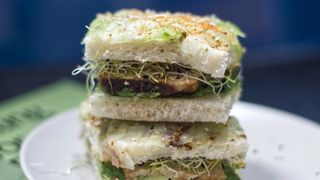 Two square sandwiches stacked on a plate, placed on a book