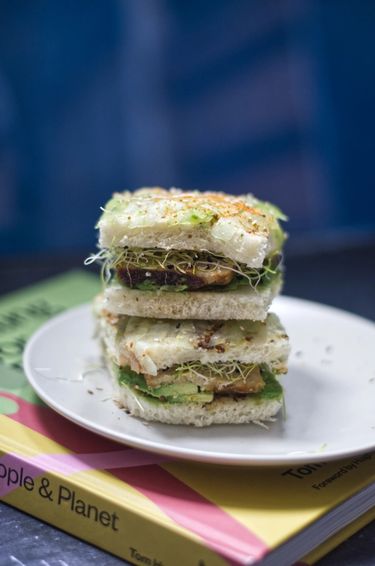 Two square sandwiches stacked on a plate, placed on a book
