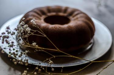 Cooked unsliced bundt cake on a silver cake plate, with dried flowers as decoration 
