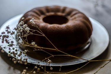 Cooked unsliced bundt cake on a silver cake plate, with dried flowers as decoration