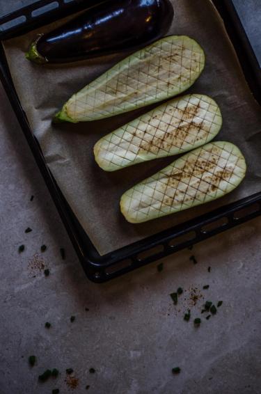 Four halves of raw aubergine on a baking tray 
