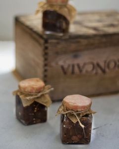 Three full jars on a table with a white cloth and a wooden box.