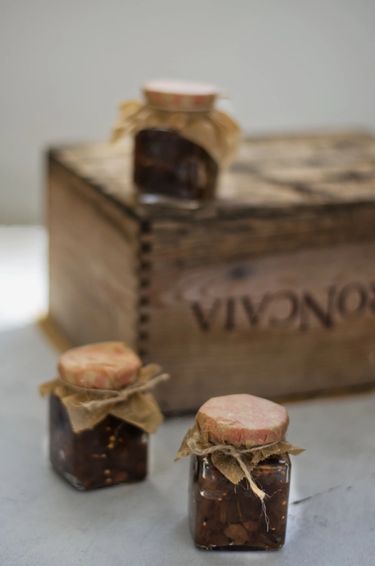 Three full jars on a table with a white cloth and a wooden box.