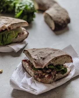 Several slices of Maltese ftira bread or hobz biz-zejt — a sandwich stuffed with tuna, capers, olives, goats cheese, lettuce, pickled vegetables and more.